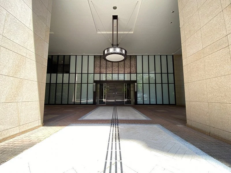 ビルの入り口のロビー、ガラスの扉と照明のシャンデリアが見える