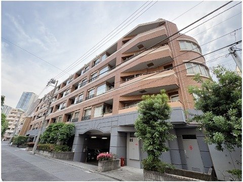 複数階建てのマンション外観と周囲の街路樹。
