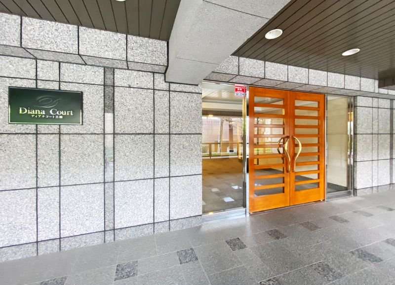 建物の入口の木製ドアの左側に緑色の看板があり、