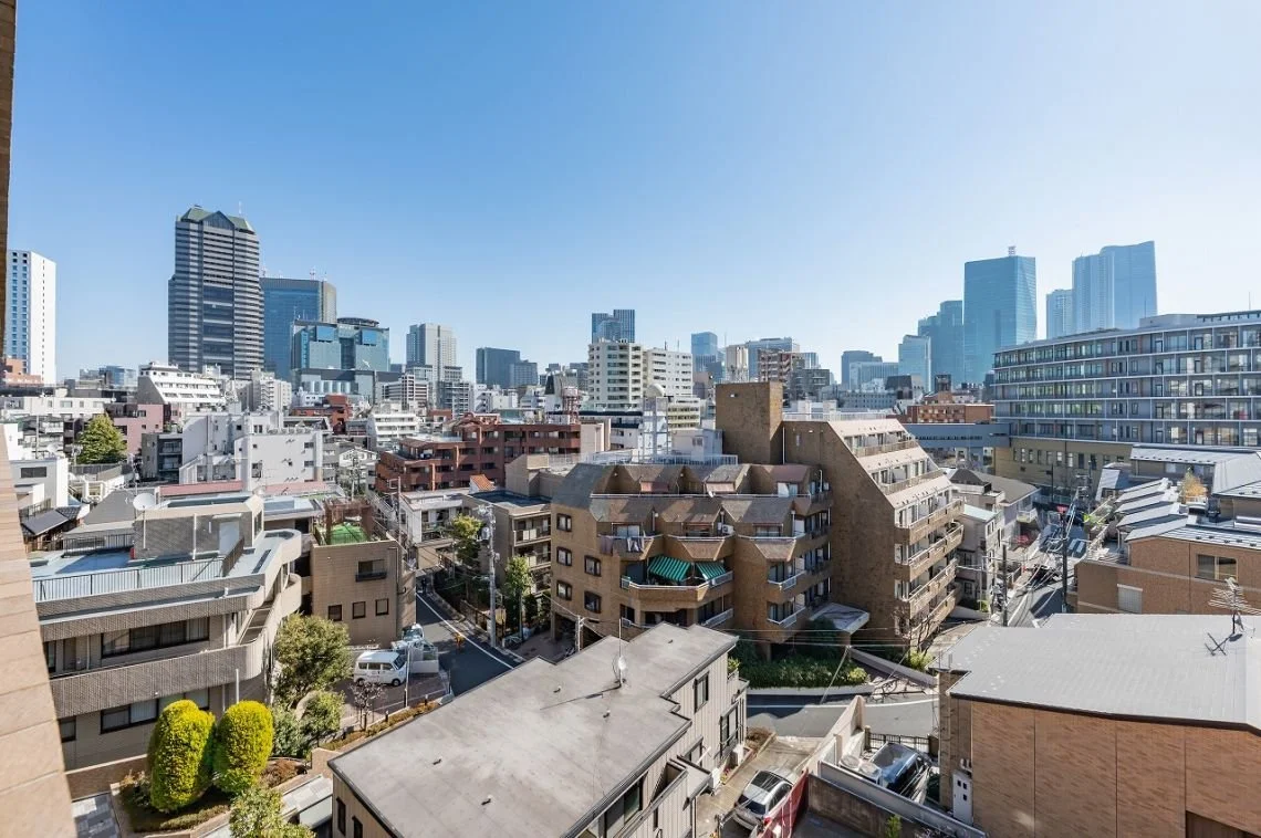 都市の高層ビルと中層ビルが並ぶ市街地の景色。青空が広がっている。