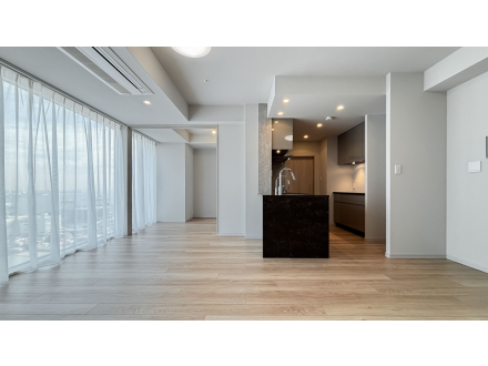 広々としたリビングルームと開放的なキッチンエリアで、窓から自然光が差し込む空間