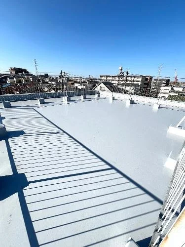 青空の下の屋上の防水層とフェンス