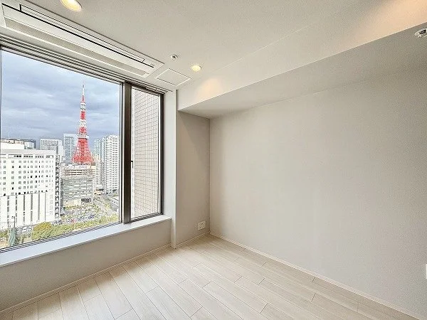 都市の高層階の窓から東京タワーと都市の景色が見える、空き部屋の室内