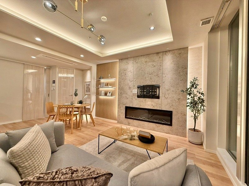 モダンなリビングルームの interior with gray sofa, coffee table, fireplace, bookshelf, and potted plant.