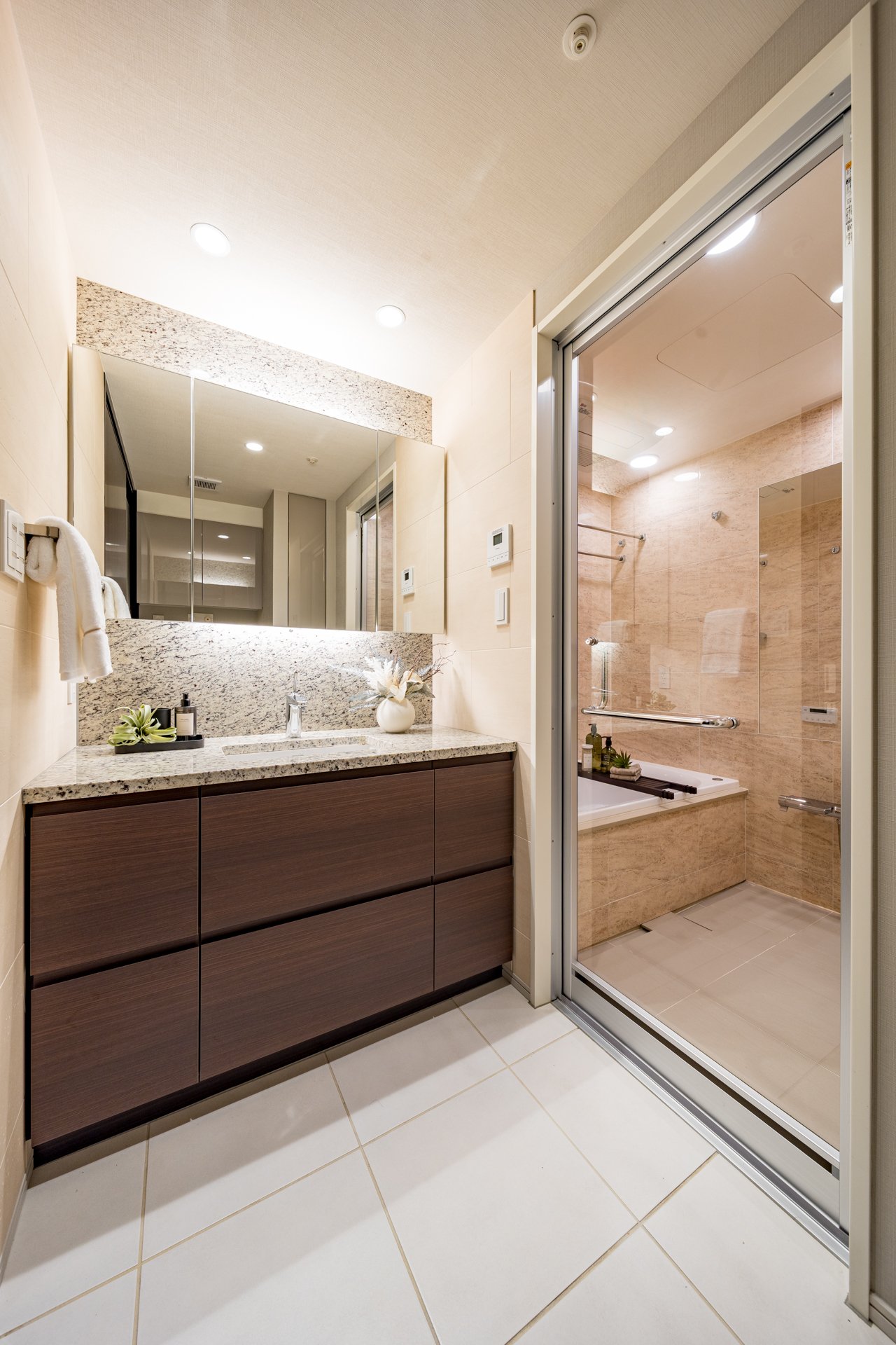 洗面所と浴室が仕切られたバスルームの写真。洗面台には鏡と装飾品が置かれている。