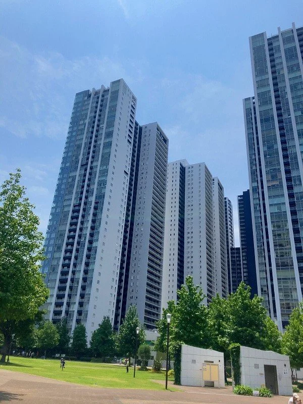 高層ビルが立ち並ぶ都市の風景と、公園の木々や遊歩道
