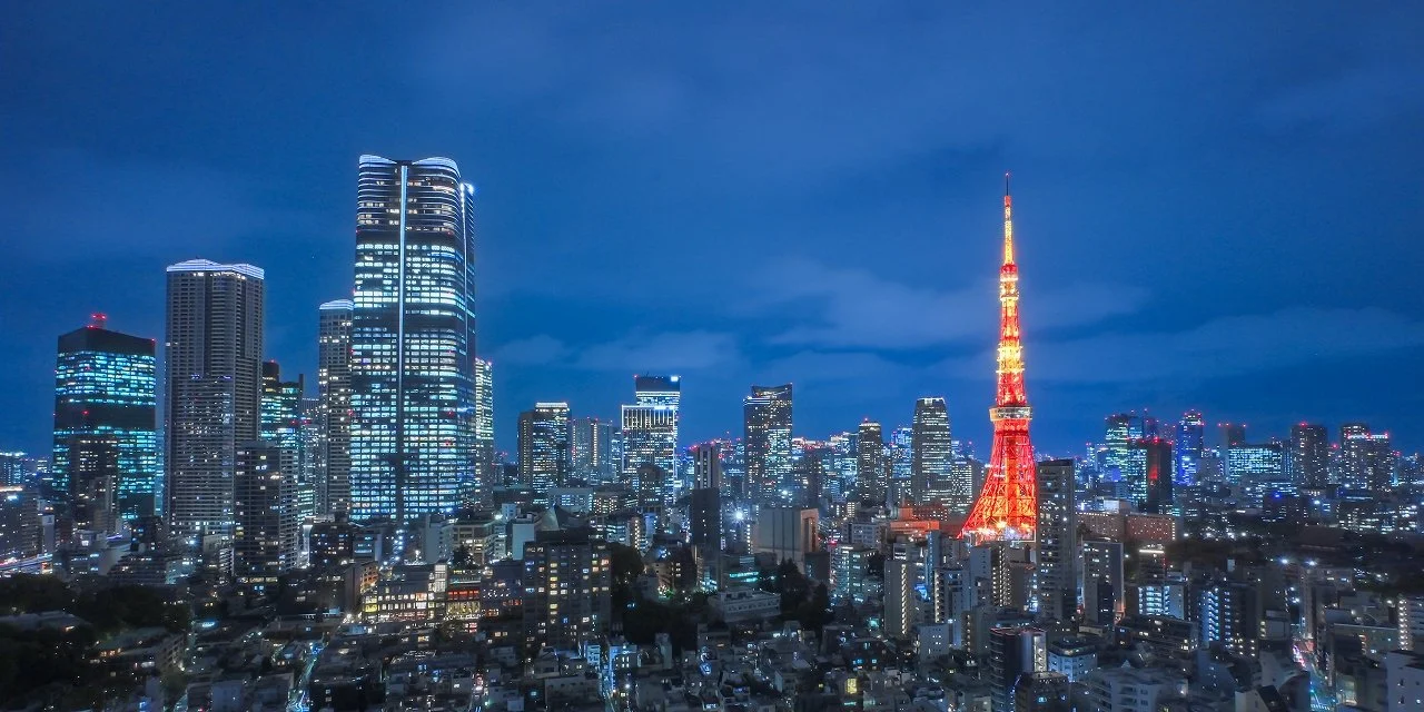 東京の夜景。東京タワーが赤くライトアップされている。高層ビルが立ち並ぶ市街地が広がっている。