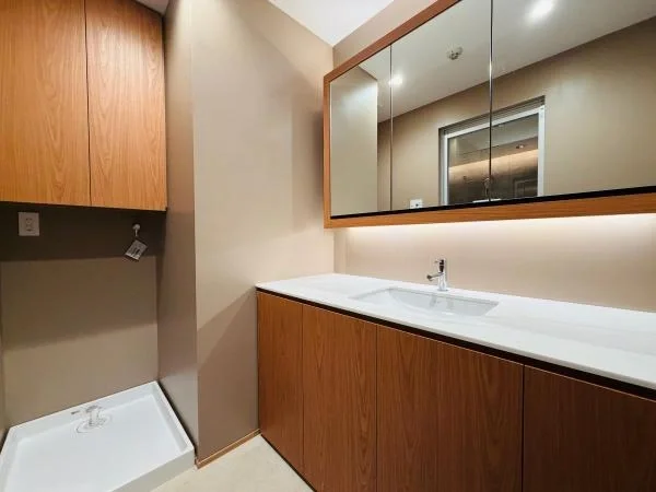 洗面台と鏡が設置されたシンプルなバスルームの洗面エリア