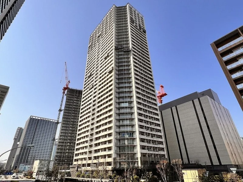 高層ビルが立つ都市の風景、青空の下で工事中の建物も見える