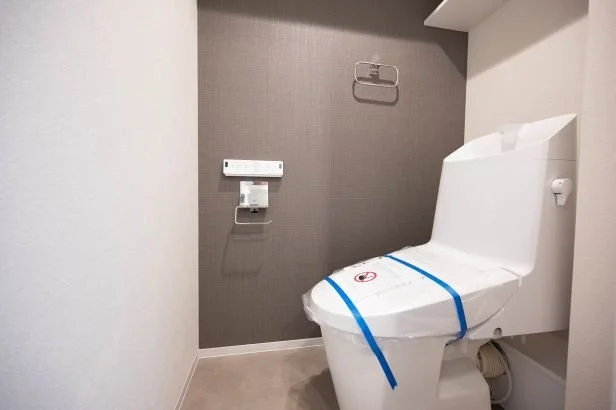 新しいトイレとトイレットペーパーホルダーが設置された清潔なトイレルーム。