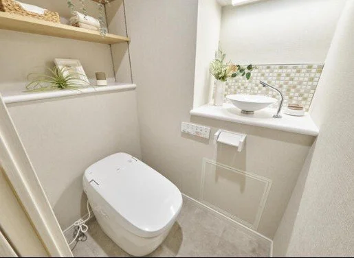 白いトイレと棚に飾られた植物や小物があるです。