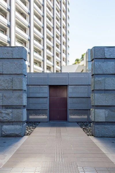 高層ビルの前にある門の様子。門は金属製で、大きな石で囲まれている。