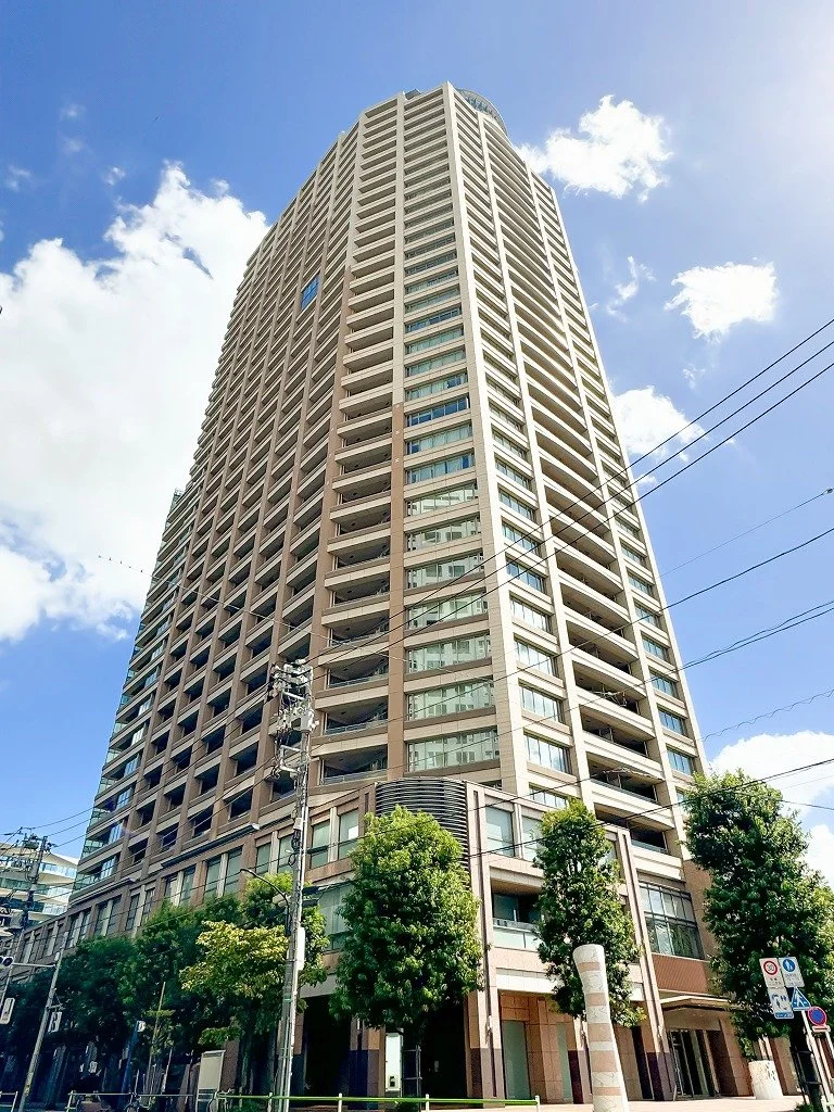 高層ビルと青空、数本の木と街路樹、電柱と電線