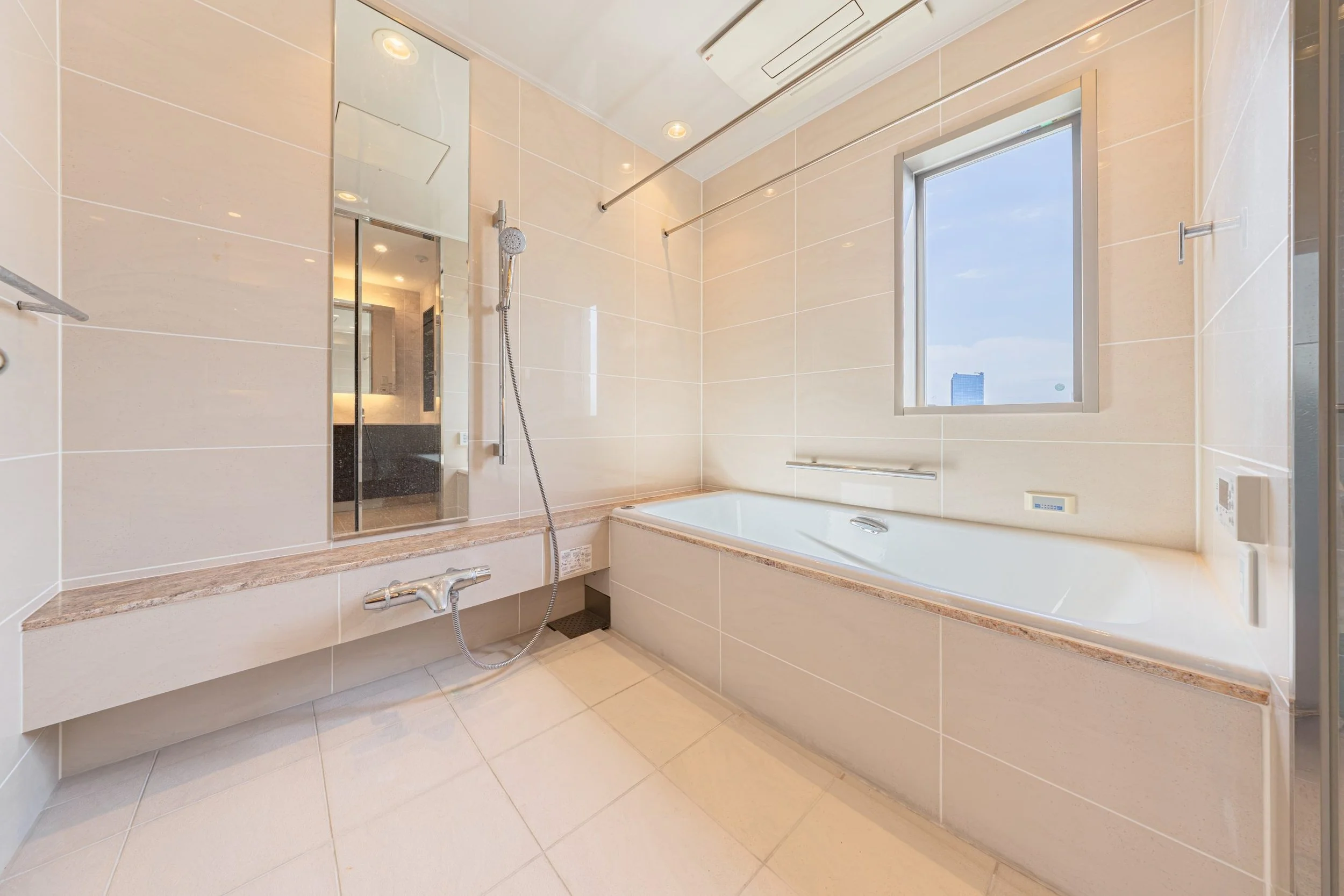 明るいバスルーム with浴槽とシャワー、鏡、窓からの景色