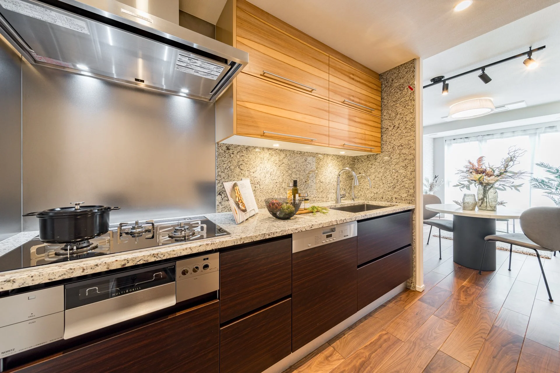 モダンなキッチンとダイニングルームの interior design, 木製のキャビネットと大理石のカウンター、ガスコンロとシンクがある