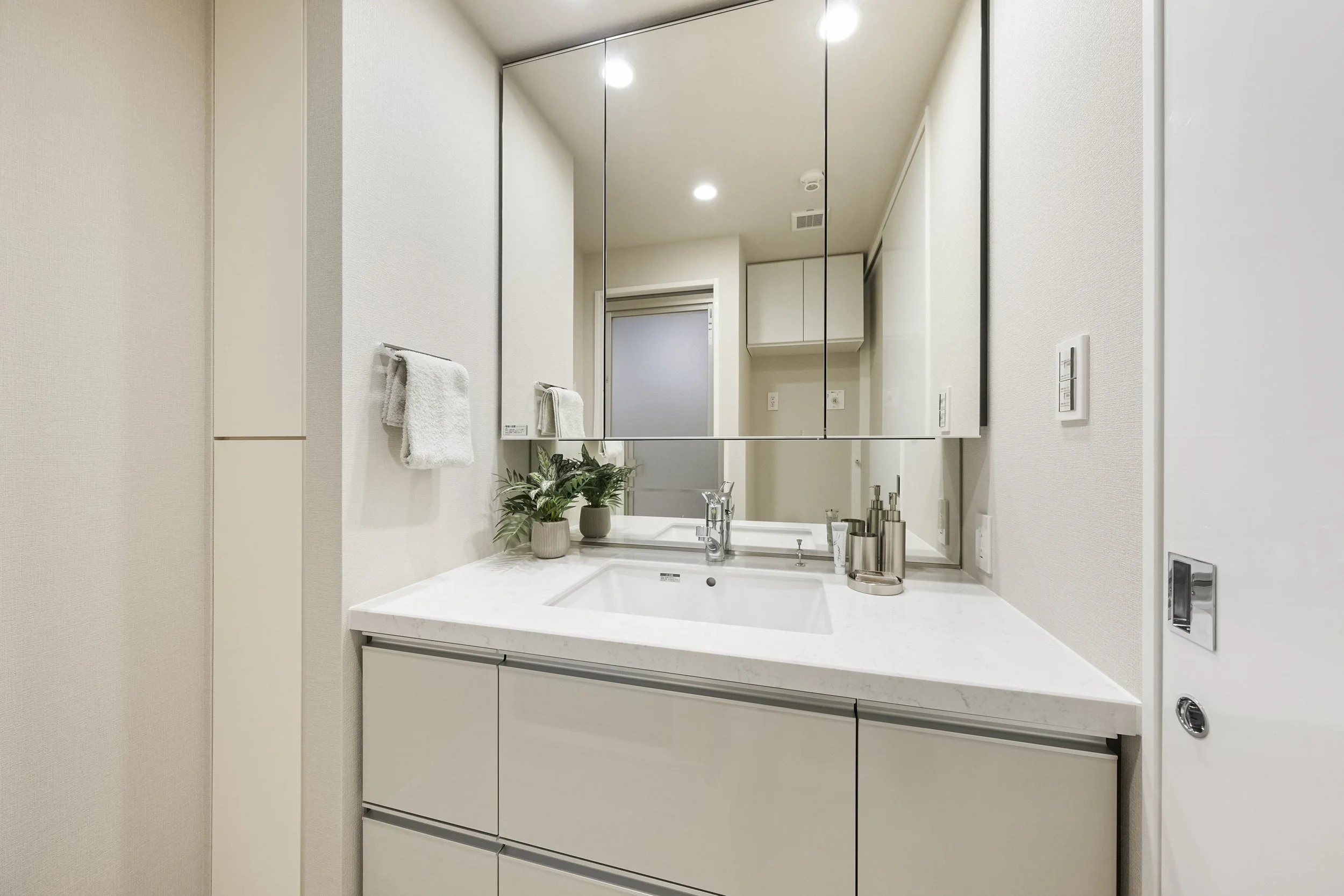 白い洗面台と鏡、鏡に映る洗面所の様子