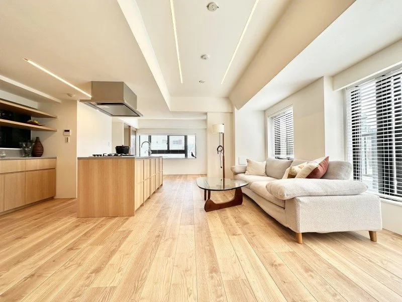 白と木材を基調としたリビングルームとキッチンが見える interior.