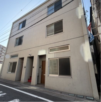 3階建ての白い建物と窓、入口部分が写っている