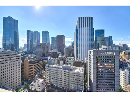 東京の高層ビルが並ぶ都市の景色、青空と太陽が見える