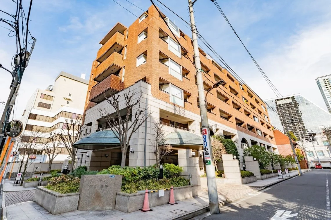 都市の通りにある高層のレンガ色のマンション」}»}