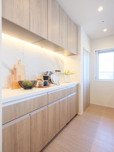 白いキッチンカウンターの上にいくつかの食器と調理道具、窓がある明るいリビングルーム