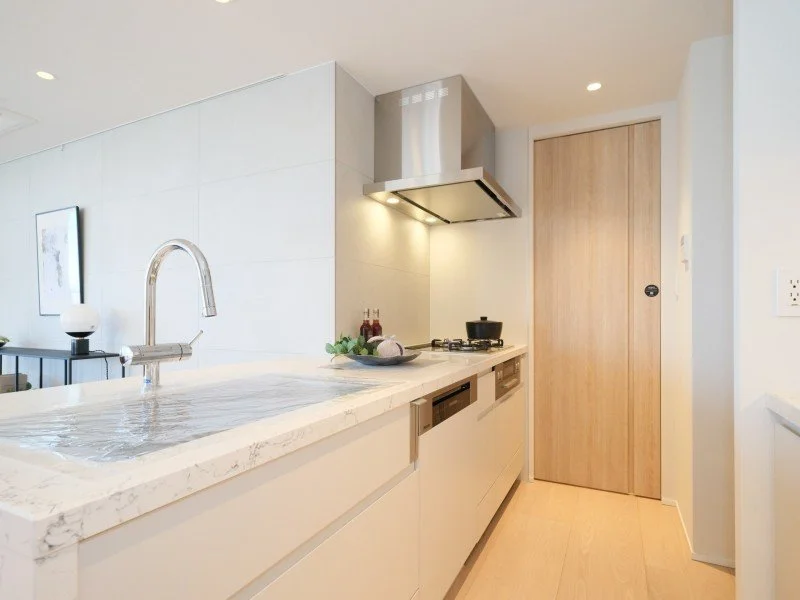 白いキッチンカウンターとコンロ、換気扇のあるキッチンの内部の写真