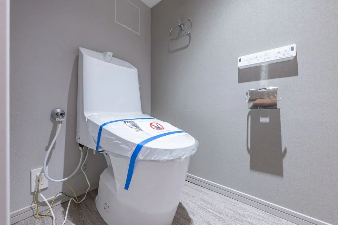 新しい高機能のトイレ、壁に紙巻き紙とリモコンが設置されている