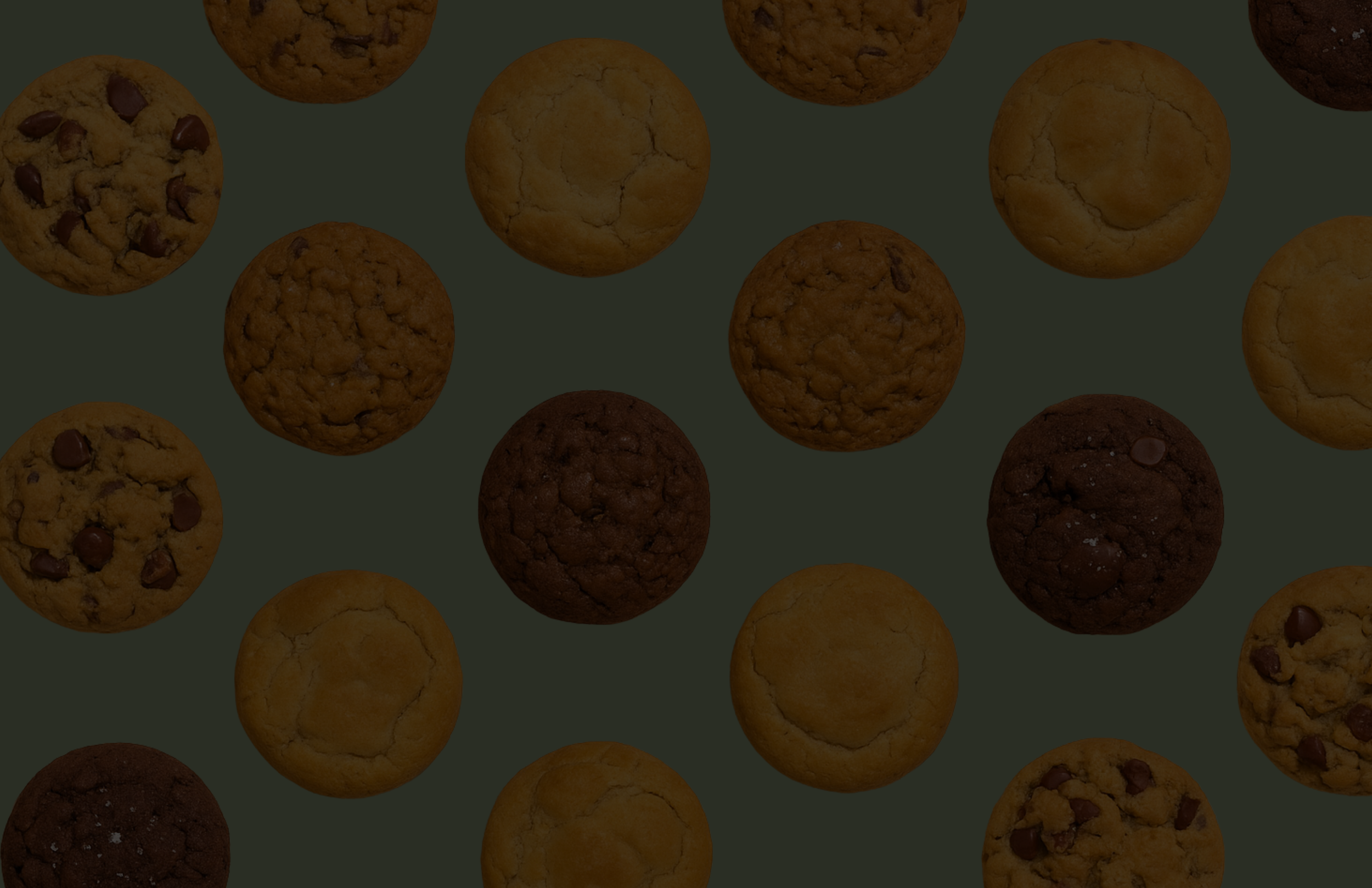 Assorted cookies aligned on a surface, including chocolate chip, oatmeal, and sugar cookies.