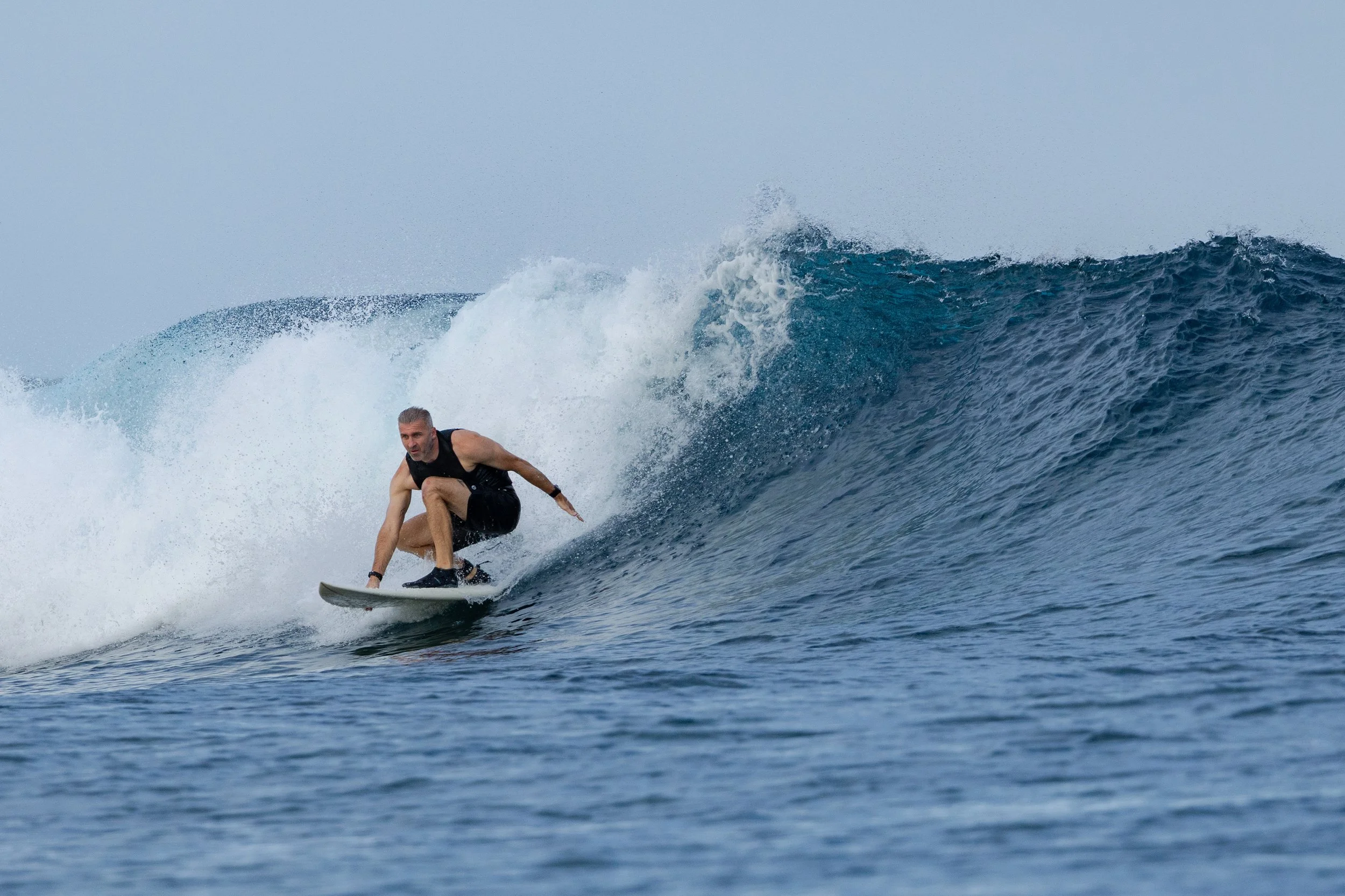 Man surfing on a large ocean wave during daytime