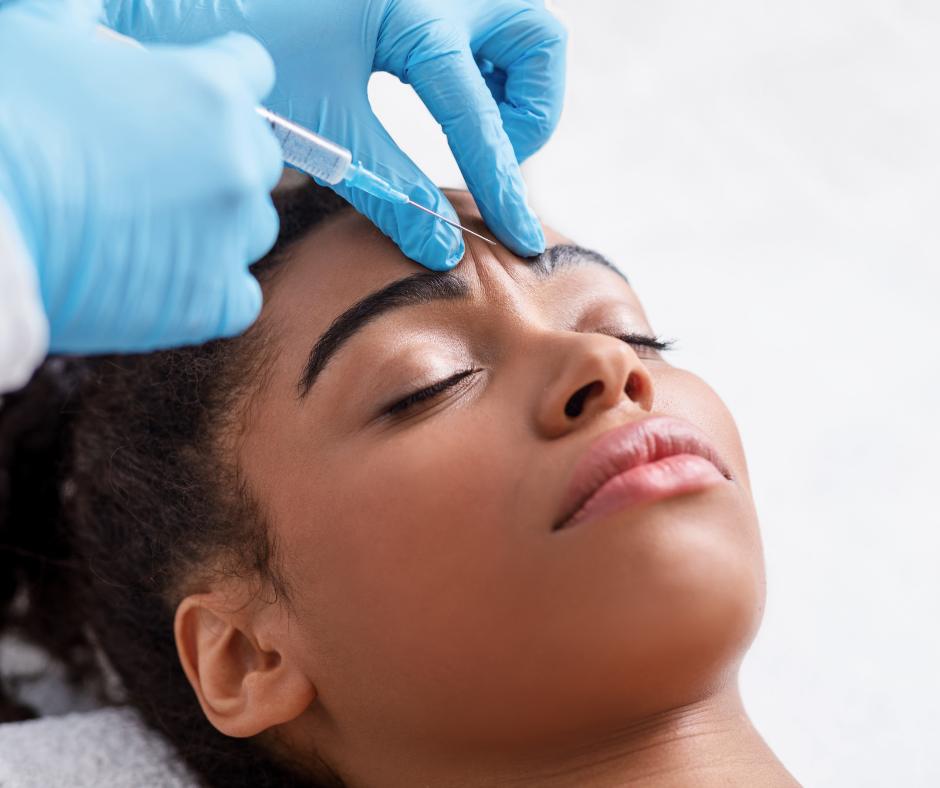 A close-up of a healthcare professional’s gloved hand administering a Botox injection into a patient’s forehead or brow area.