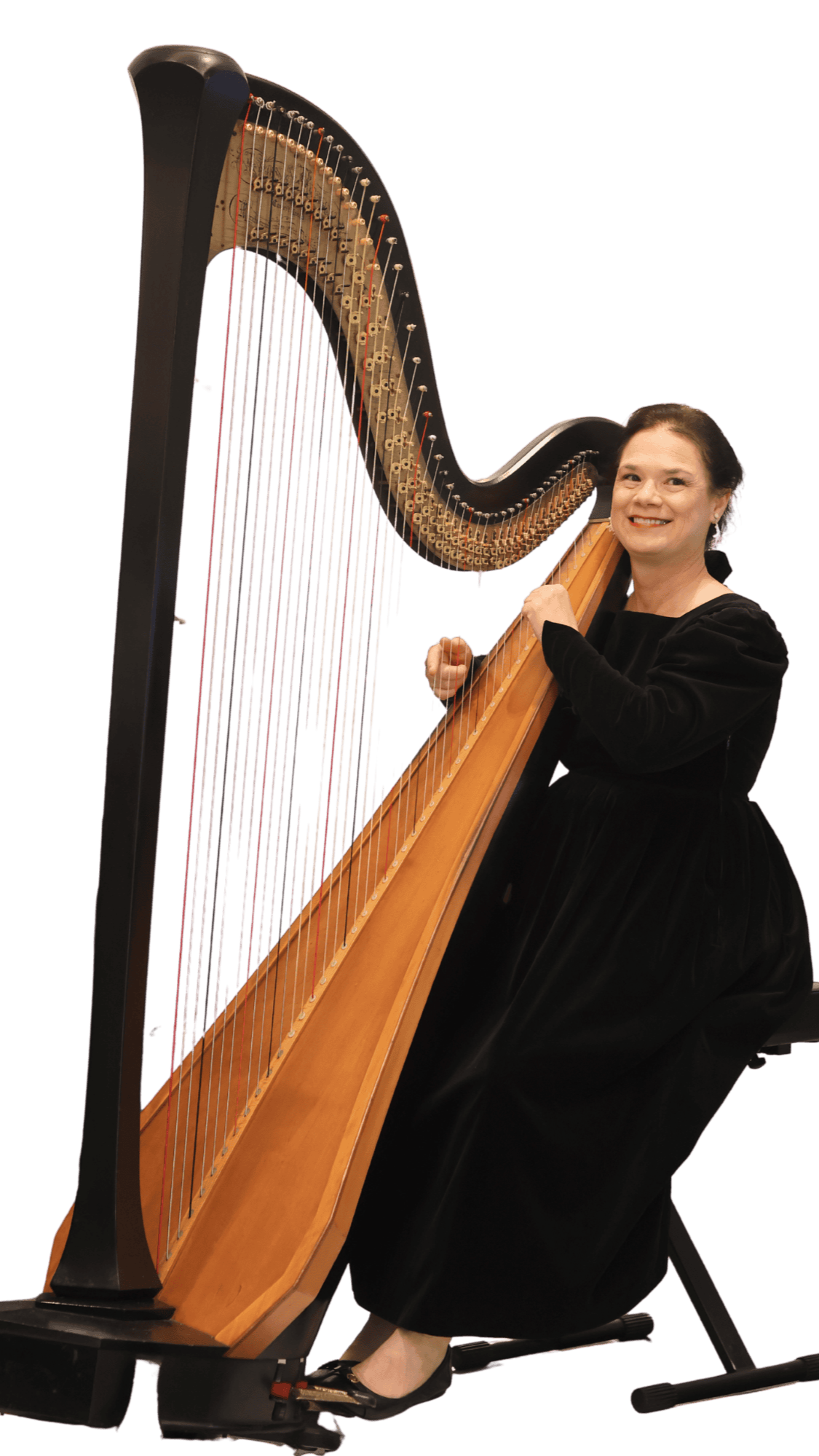 A woman in a black gown plays a large black pedal harp and smiles.