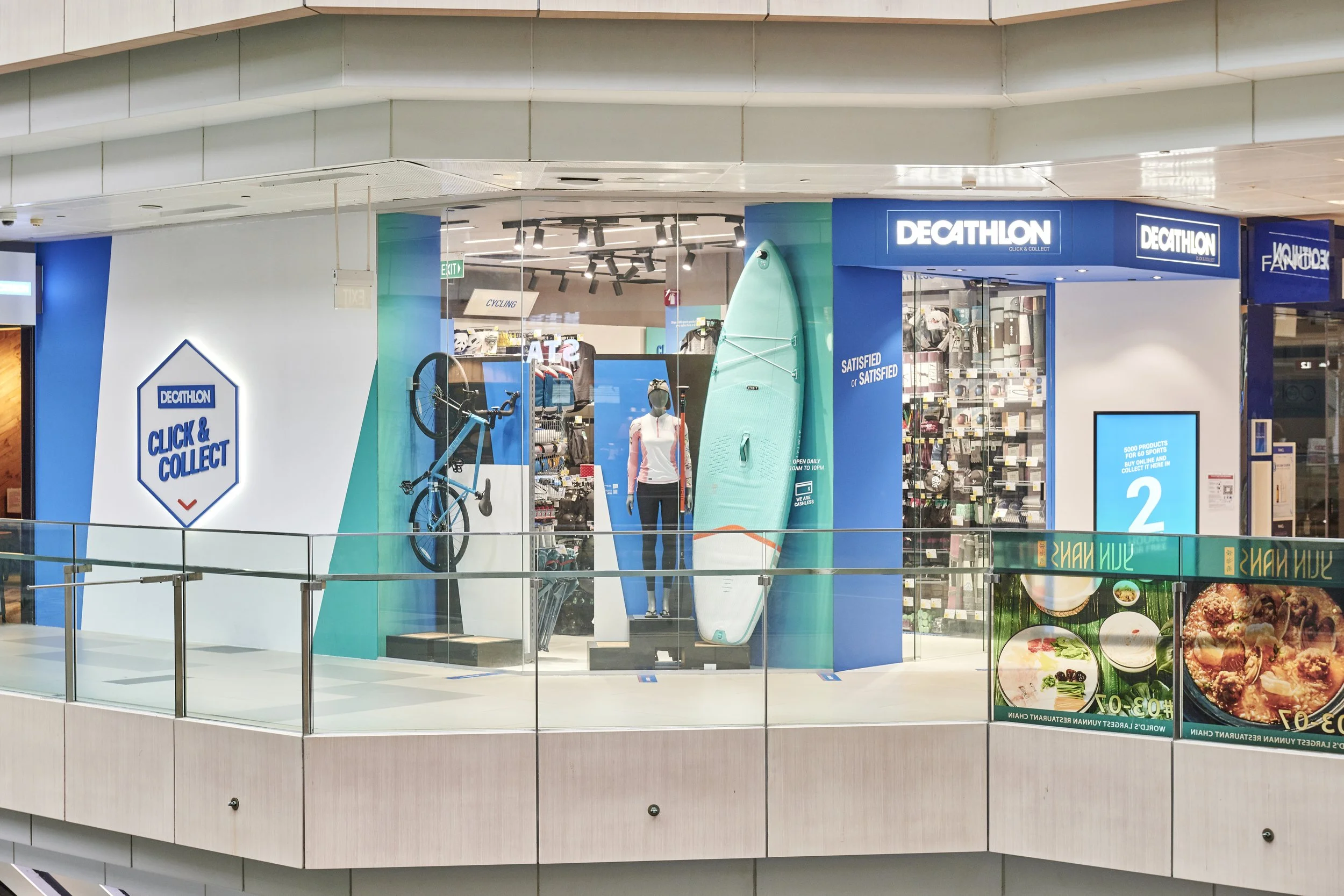 Decathlon store inside a shopping mall, displaying bikes, paddle boards, mannequins, and various sporting goods