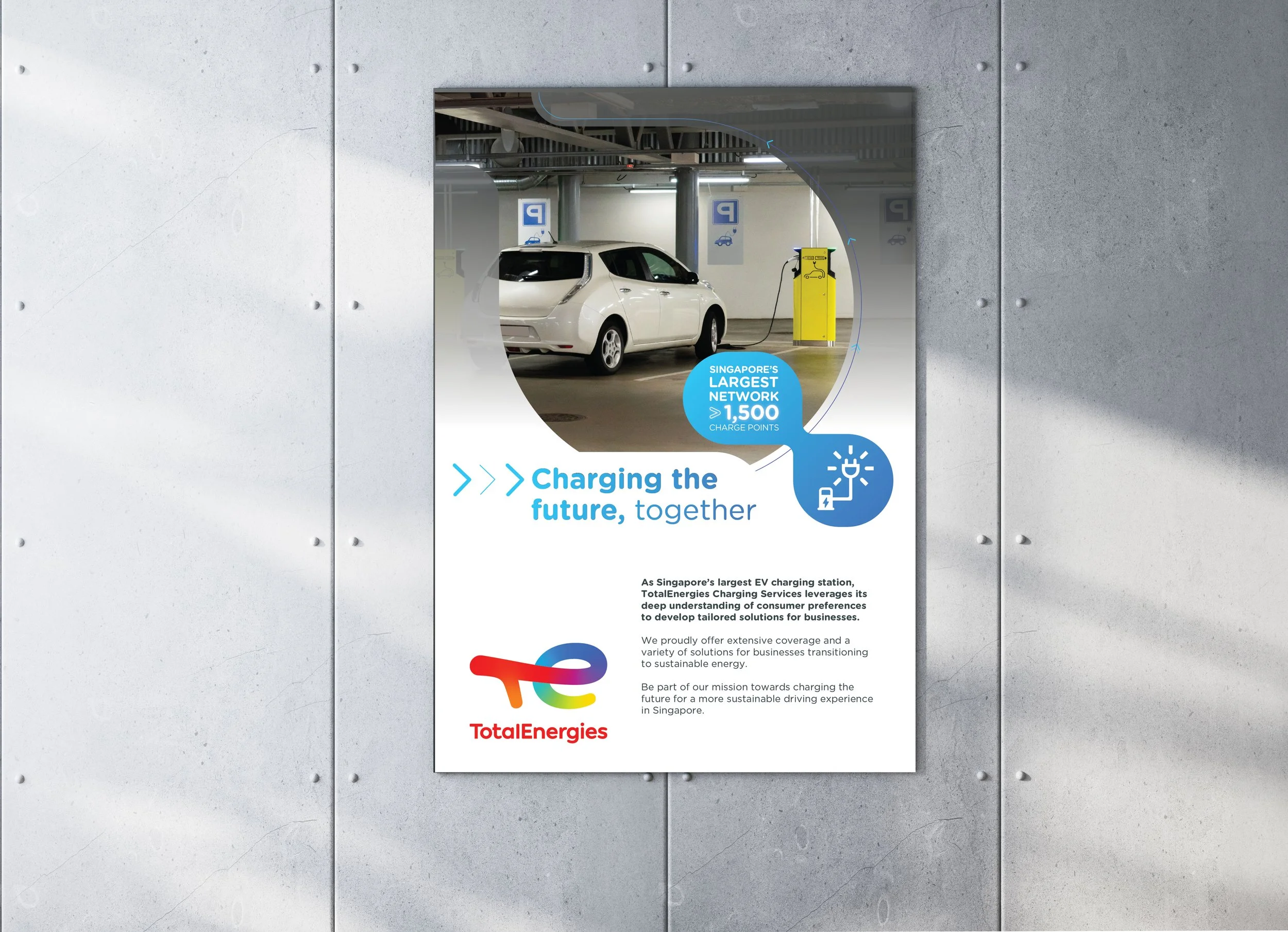 Advertisement poster promoting electric vehicle charging station services by TotalEnergies at Singapore's largest EV charging station, featuring a white electric car and charging point, with text emphasizing the station's large network and sustainable energy focus.