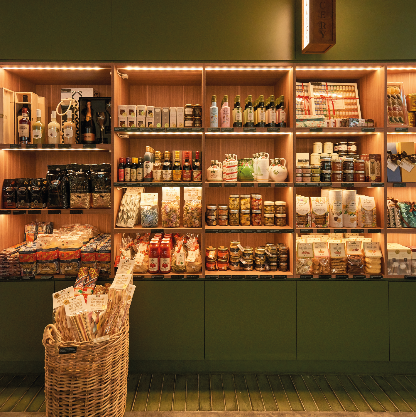 Shelves filled with various gourmet food and beverage products, including jars, bottles, and packages, in a store display with warm lighting.