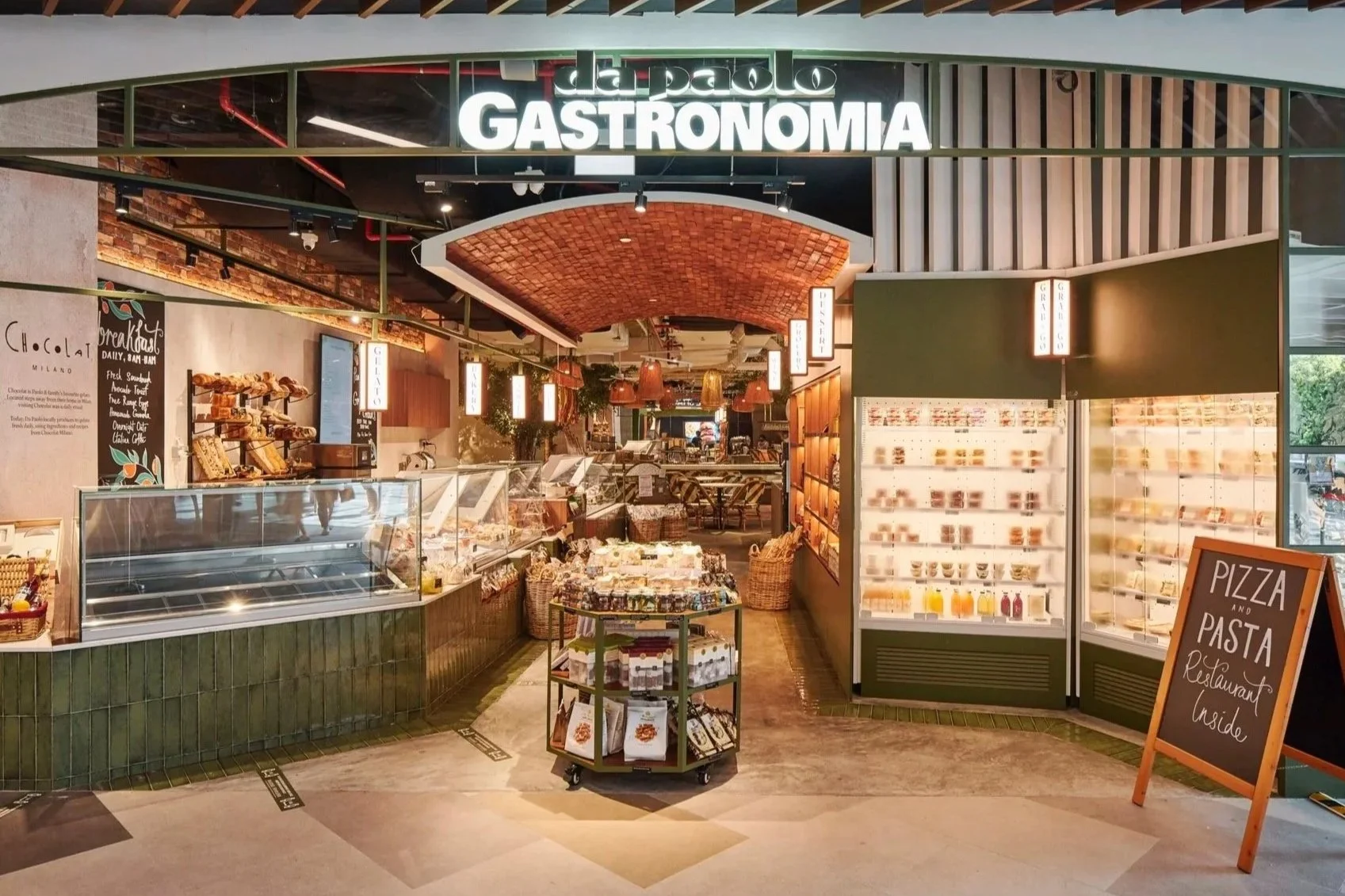 Entrance to a gourmet grocery & cafe called 'Gastronomia,' offering various Italian foods and products, with a colorful display of items and signage inside.