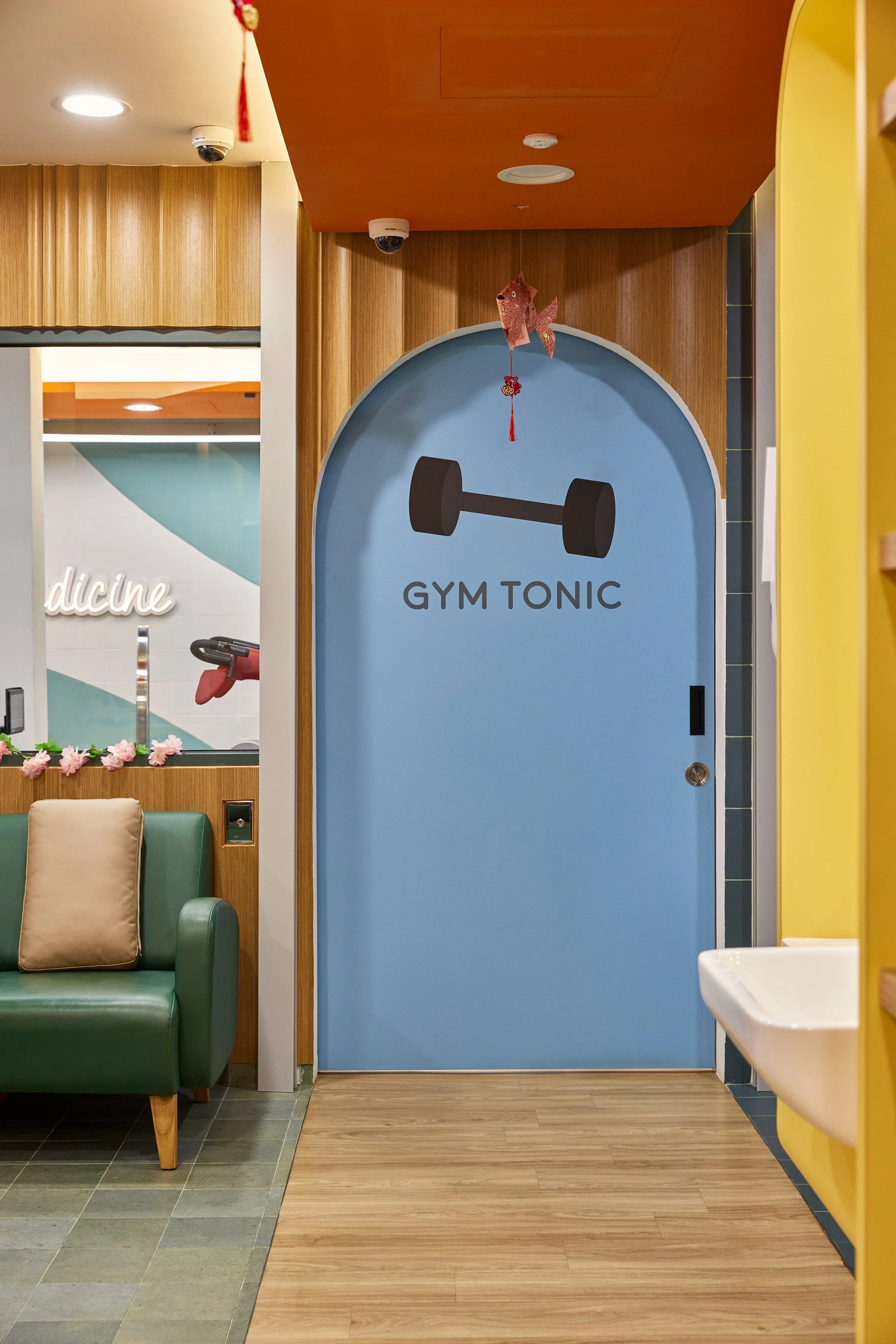 Blue door with black text 'GYM TONIC' and a black dumbbell graphic, in a colorful indoor setting.