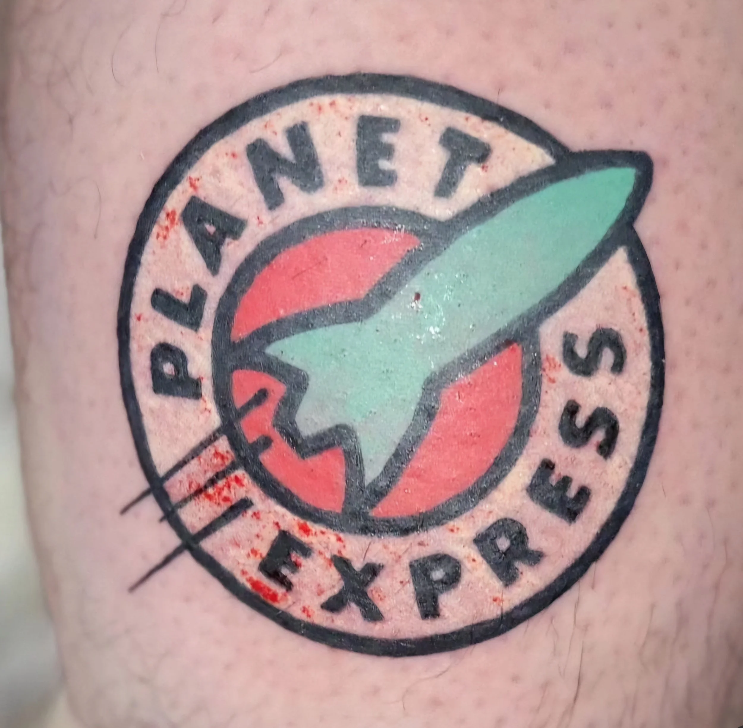 Tattoo of the American Express logo featuring a circle with a green arrow and a red background, with the words "PLAZA NET" and "AMEX PRESS" around the circle.