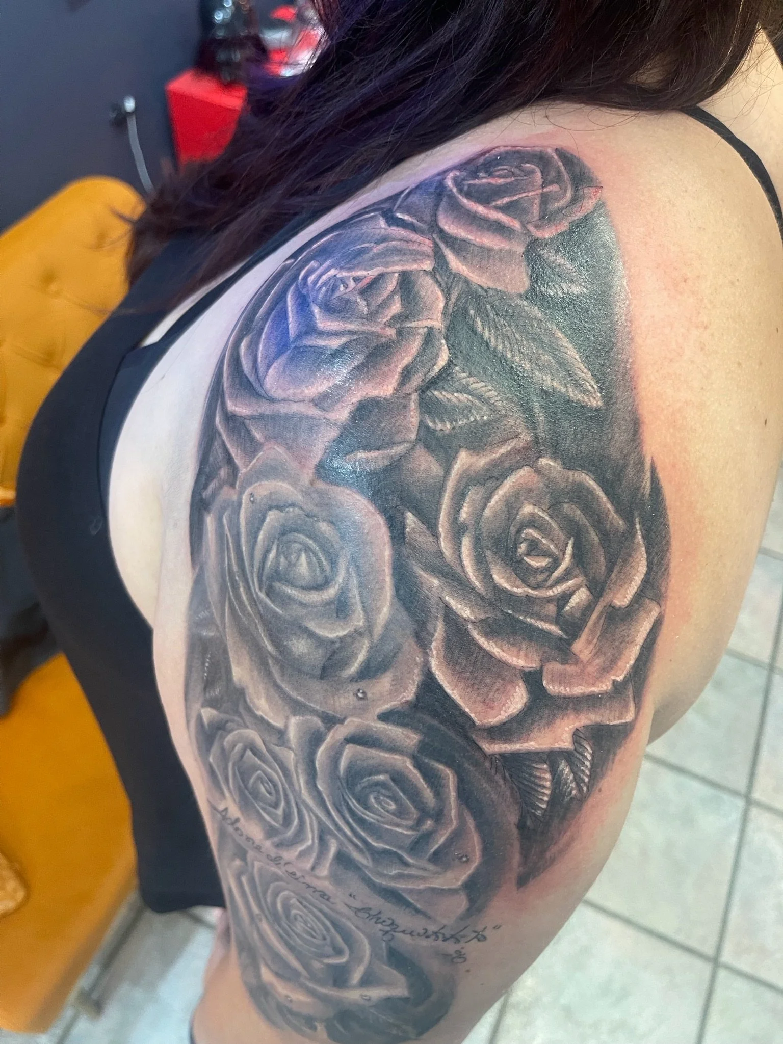 Black and gray tattoo of roses on woman's shoulder and upper arm.