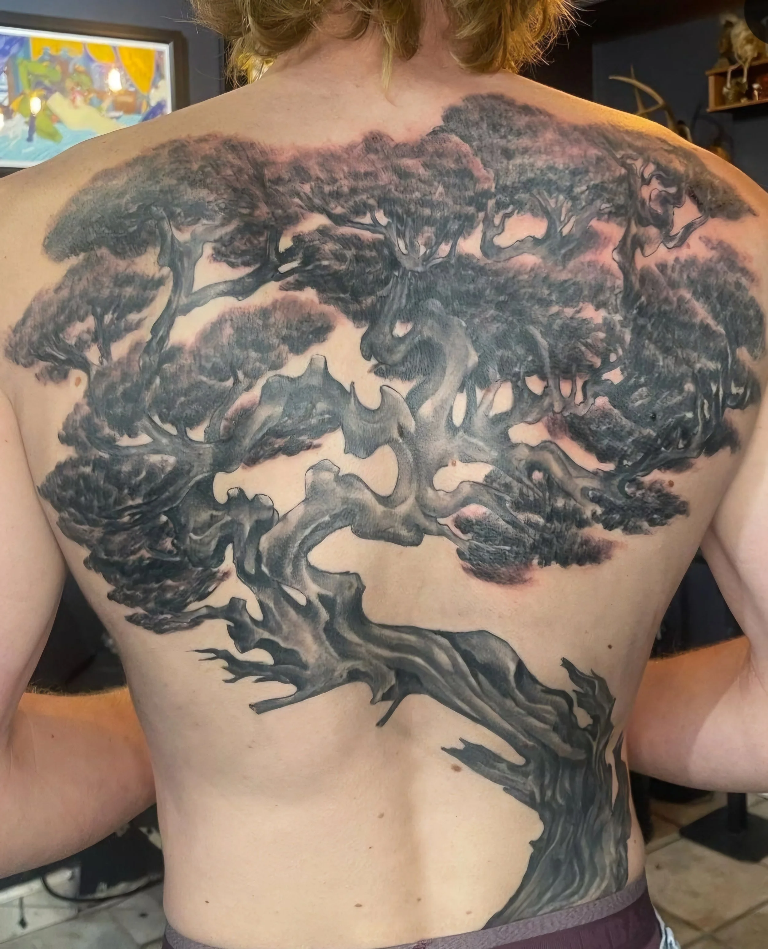 Black and gray tattoo of a large, detailed tree covering the upper chest and extending to the stomach.