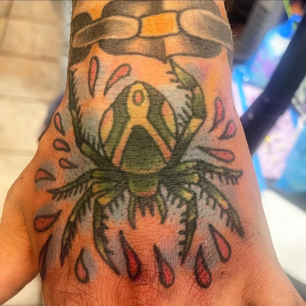 Tattoo of a frog with drops of water around it on a person's skin.