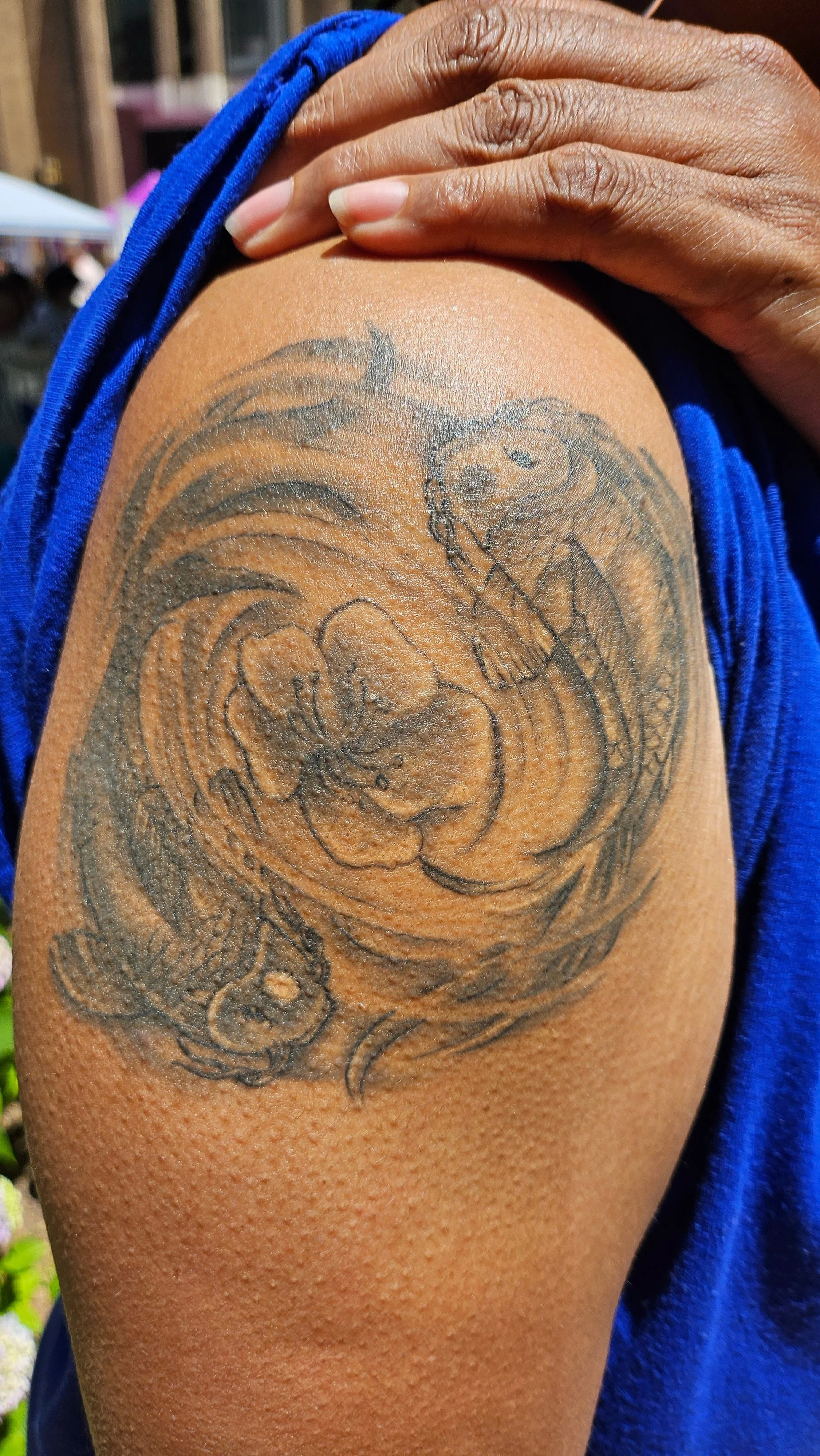 A shoulder tattoo of a snake and a woman with a swirling background.