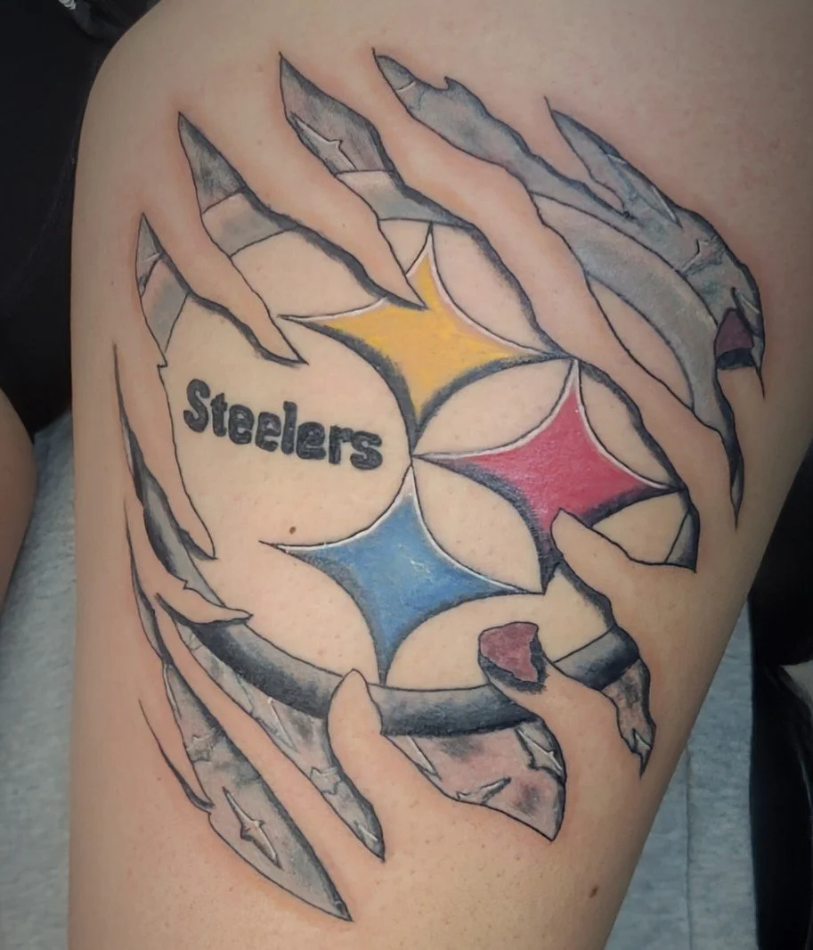 Tattoo of the Pittsburgh Steelers logo with a torn paper effect, revealing the team name and colors underneath.