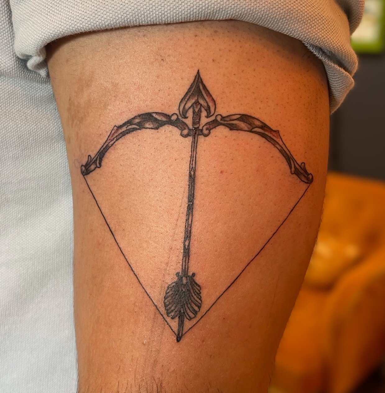 Black and grey bow and arrow on a clients arm in fine line.