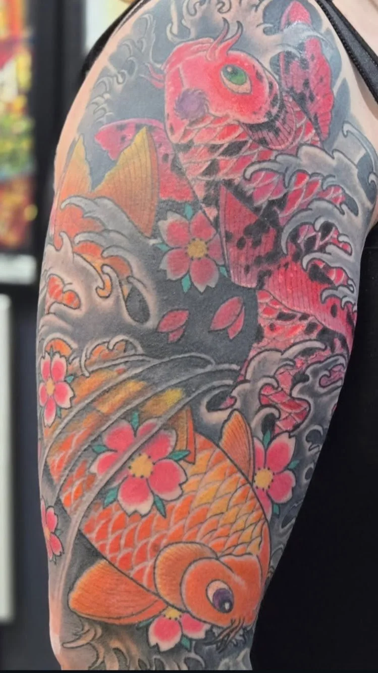Colorful traditional Japanese style tattoo featuring a koi fish, cherry blossoms, and waves.
