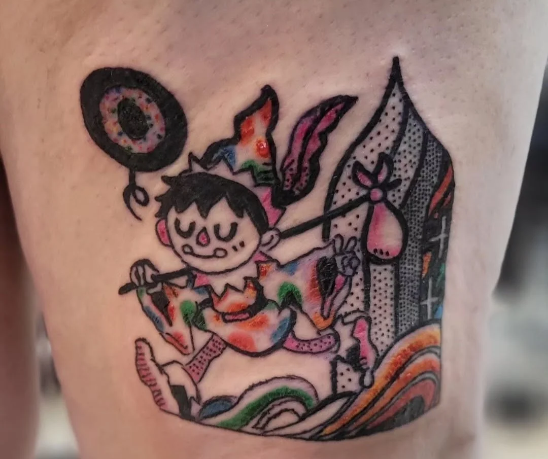 Colorful tattoo of a cartoon girl with a bow and arrow, wearing a dress with patchwork patterns, and holding a shield and spear, surrounded by rainbow waves and decorative elements.