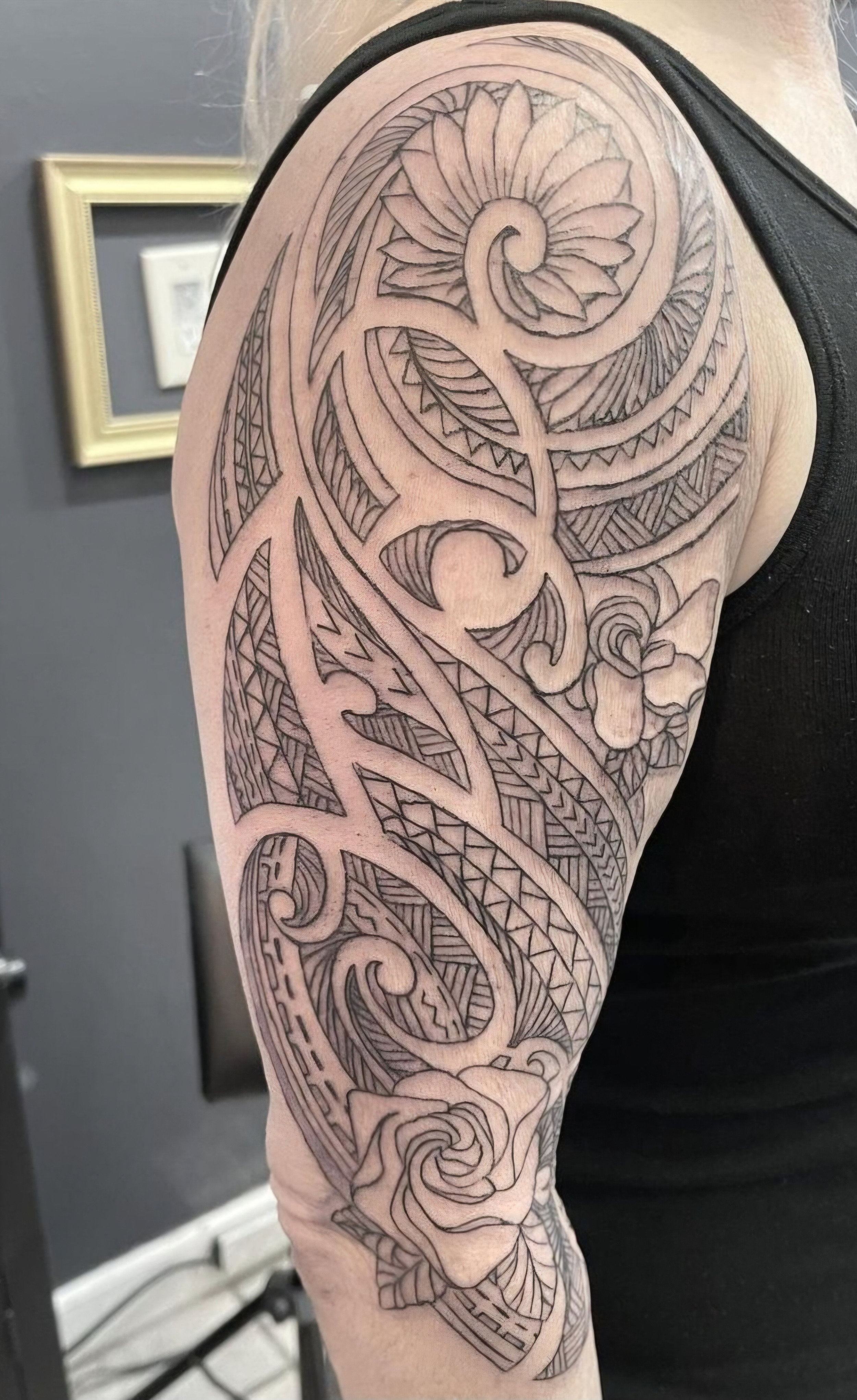 Outline of a half-sleeve tattoo featuring intricate floral and abstract geometric patterns on a person's arm.