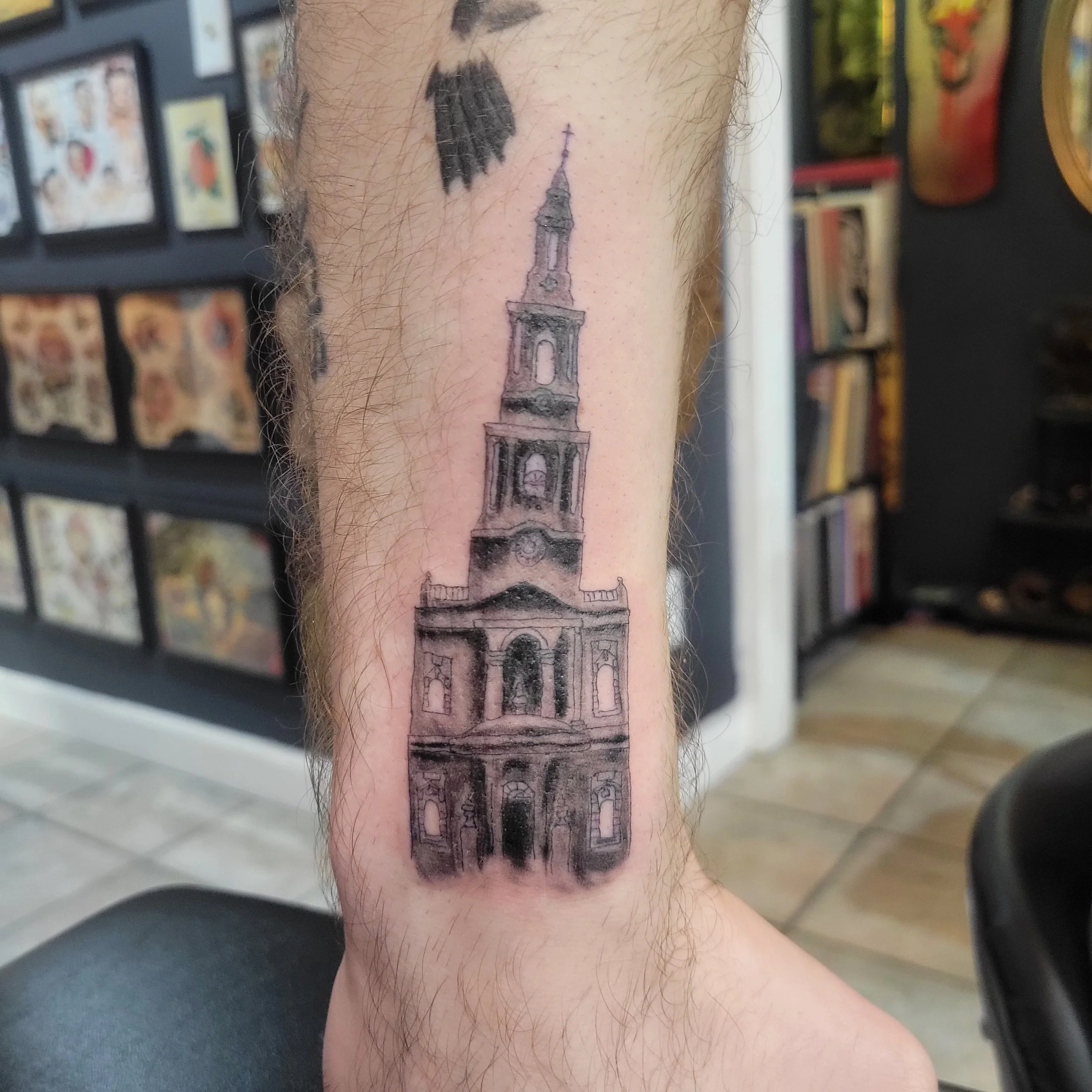 Tattoo of a church steeple on a person's leg.