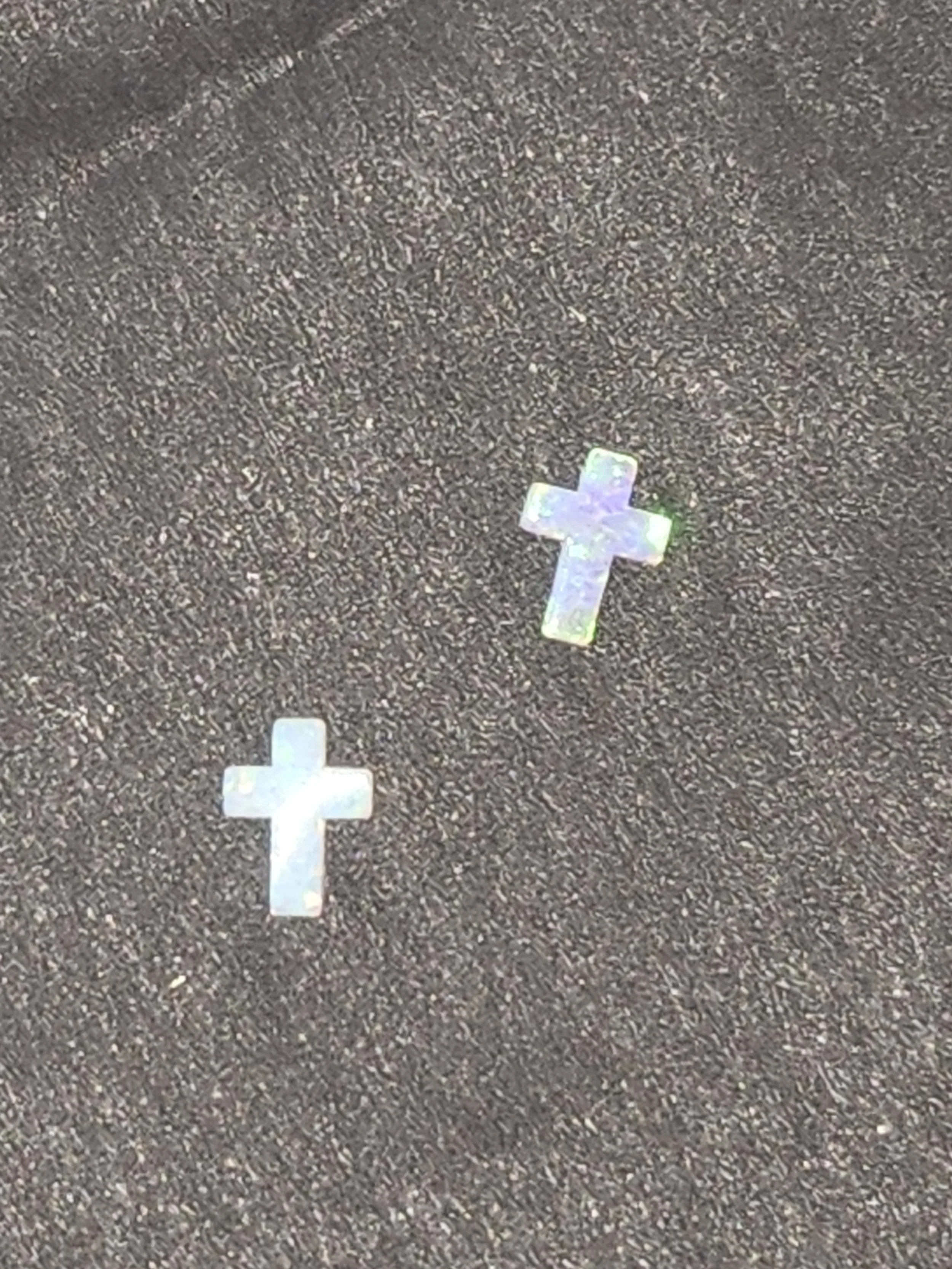 Two small holographic cross stickers on a dark textured surface.