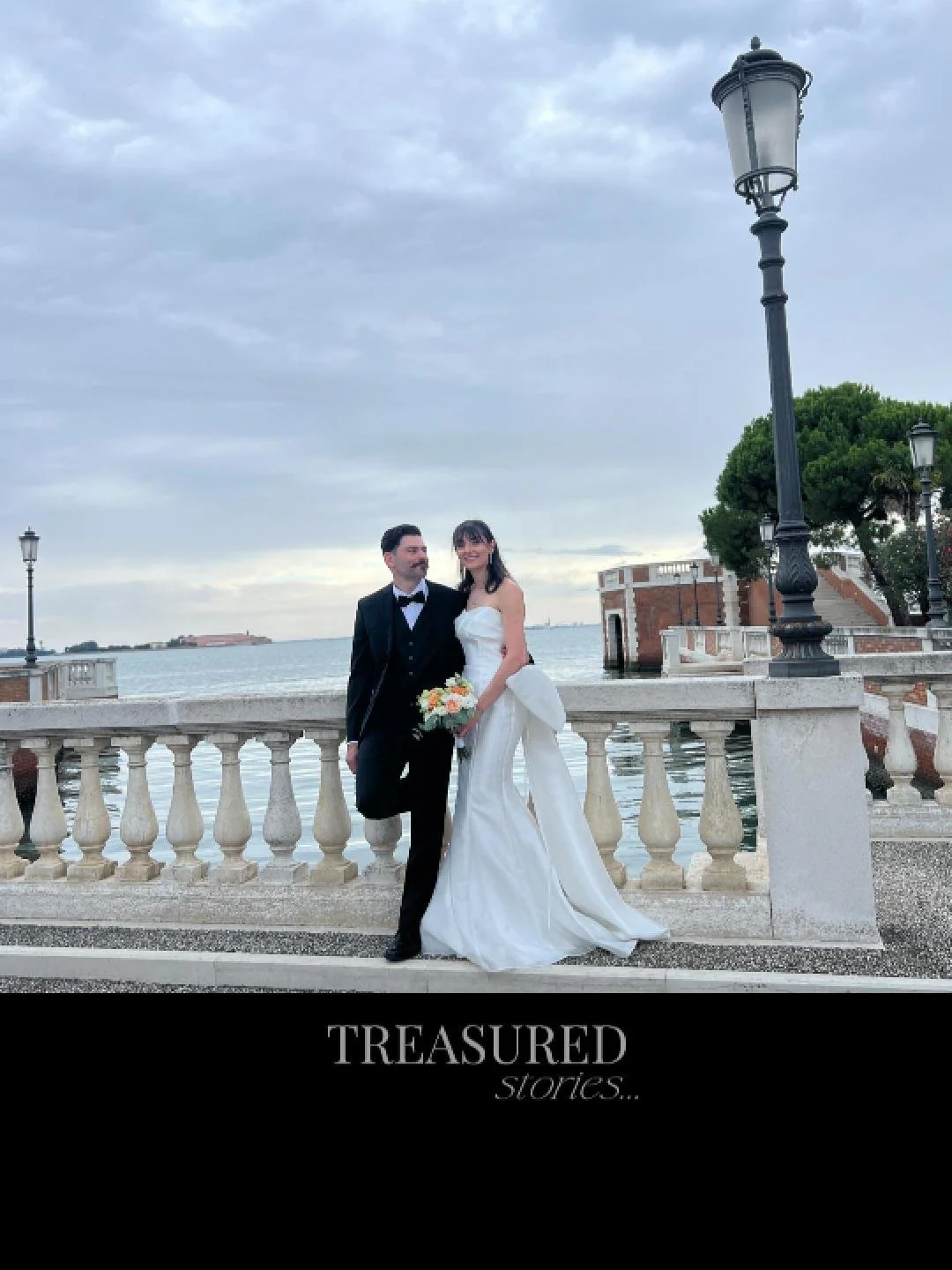 A bride and groom standing by a waterfront, dressed in wedding attire, with a railing and lamp posts in the background, and the phrase 'Treasured stories' at the bottom.