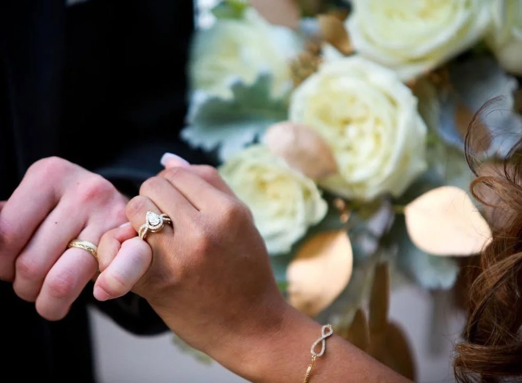 Yellow gold pear-shaped halo engagement ring and matching wedding band by Kaz Jewelry